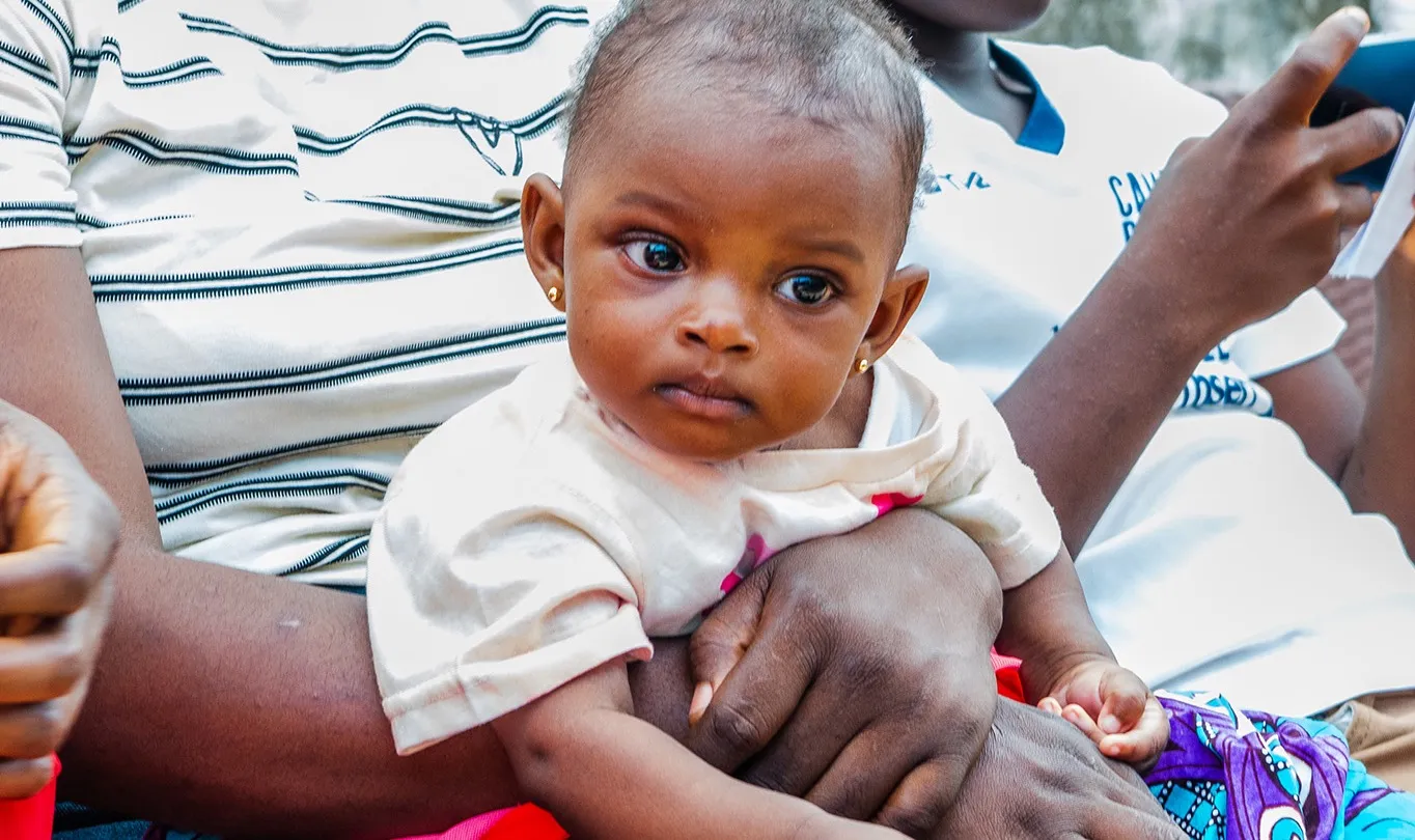 An infant resting in a parent's arms in the hospital waiting area