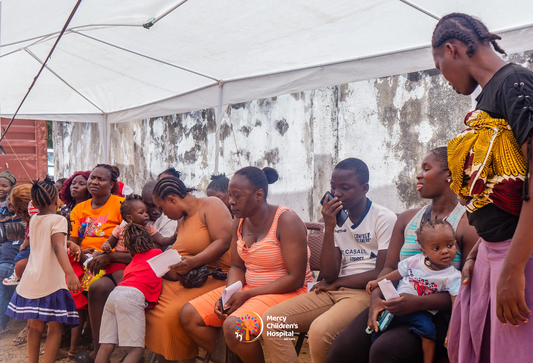 Families waiting under a tent at a free medical mission